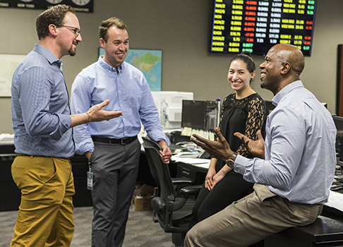 Smiling employees engaged in work discussion on Royal Dutch Shell trading floor