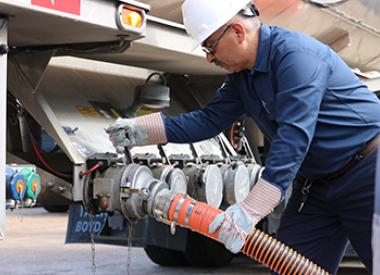 Royal Dutch Shell truck driver attaching hose to tanker
