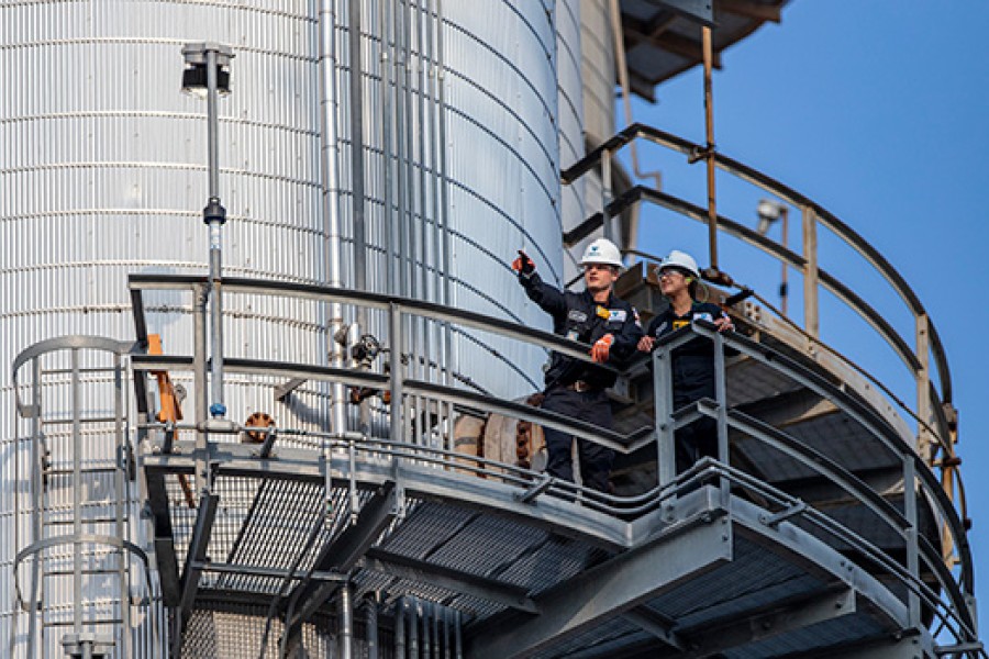 Two Royal Dutch Shell employees inspect equipment at a refinery.