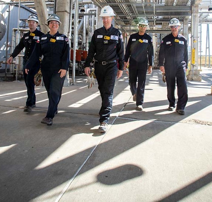 Team of five Royal Dutch Shell employees walking through the Three Rivers refinery, surrounded by equipment.